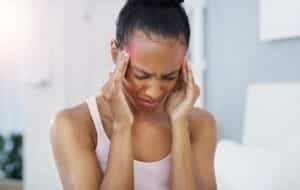 Woman closing eyes and holding her hands to her head in pain due to migraine, in need of IV Therapy, Lone Tree, CO.