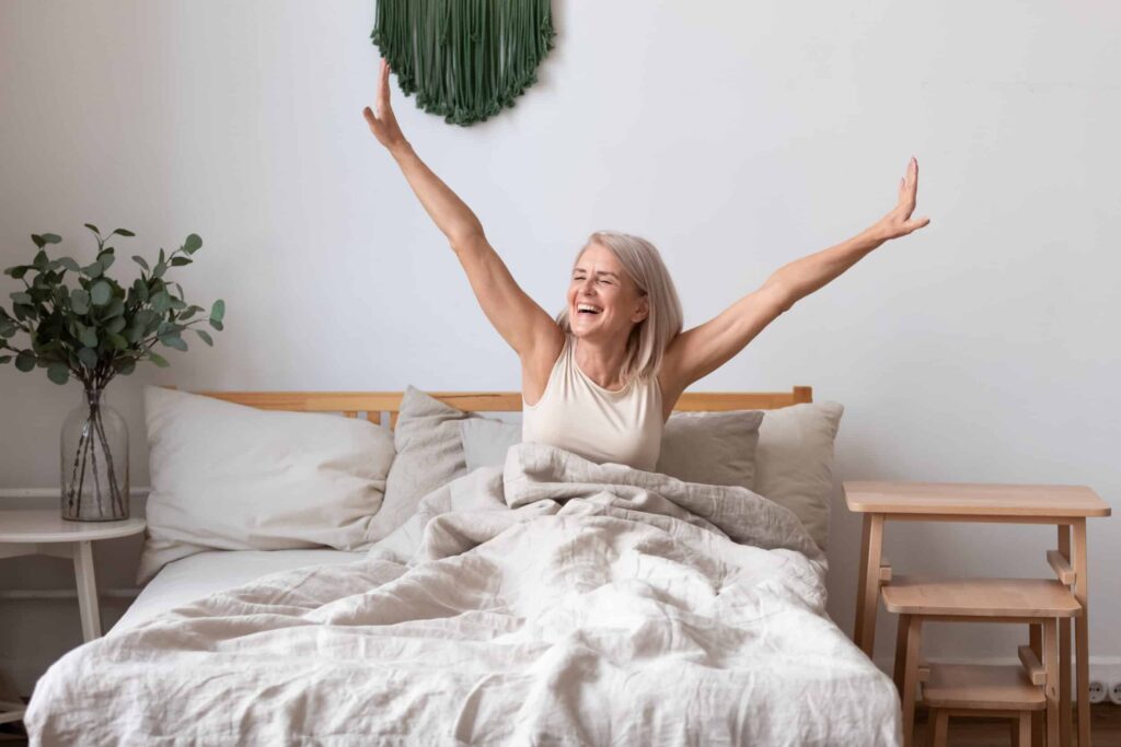 How Neurofeedback Training Can Boost Energy Levels A woman smiling and stretching as she gets out of bed