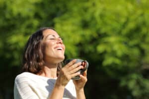 A woman smiling and holding a cup of tea