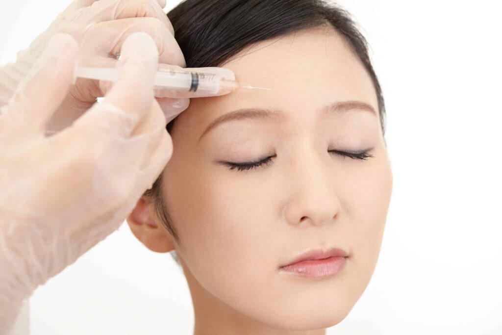 Tox for First-Timers: When to Start 1 Woman closes her eyes during a wrinkle relaxer injection in her forehead