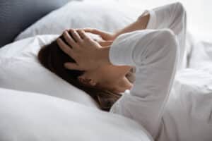 A woman lying in bed and feeling fatigued before NAD+ IV therapy
